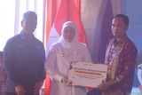 Gubernur Jawa Timur Khofifah Indar Parawansa (tengah), didampingi Direktur Utama PT Sinergi Gula Nusantara (SGN) Mahmudi (kiri), menyerahkan bantuan ke petani tebu Teguh Cahyono (kanan) saat meluncurkan kredit usaha rakyat (KUR) khusus petani tebu di Kebun Walidono, Prajekan, Bondowoso, Jawa Timur, Selasa (6/5/2025). Khofifah meluncurkan KUR khusus untuk petani tebu binaan PT SGN dengan platform pinjaman maksimal Rp500 juta. Antara Jatim/Seno/um 